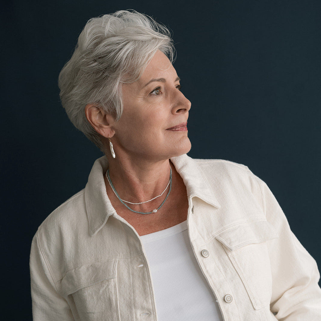 Woman with short silver hair wearing a stick pearl earring