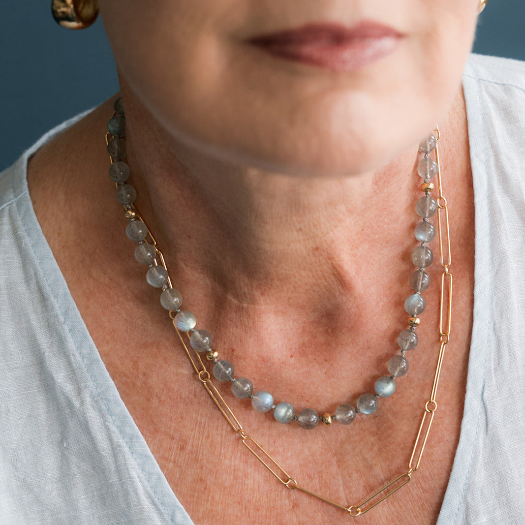 Woman wearing round labradorite gem necklace with gold beads