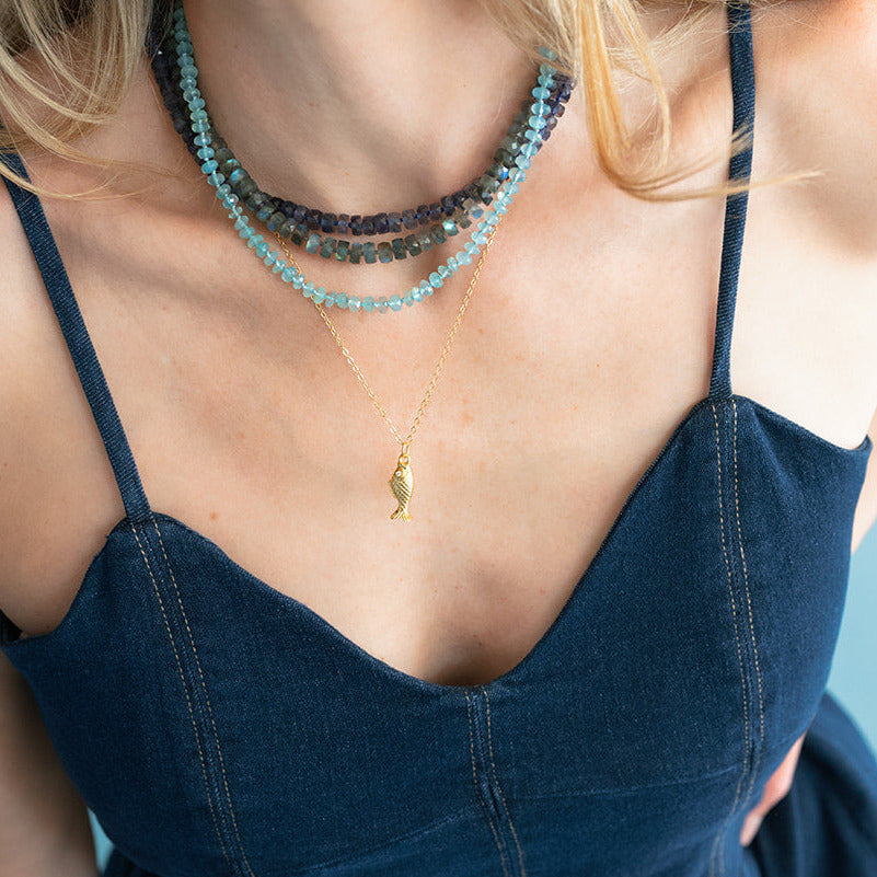 Woman wearing a navy blue dress with thin straps against a light blue background