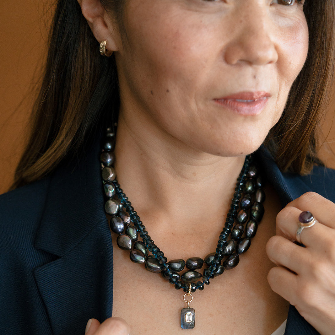 Woman wearing gold hoop and necklace stack with navy blazer