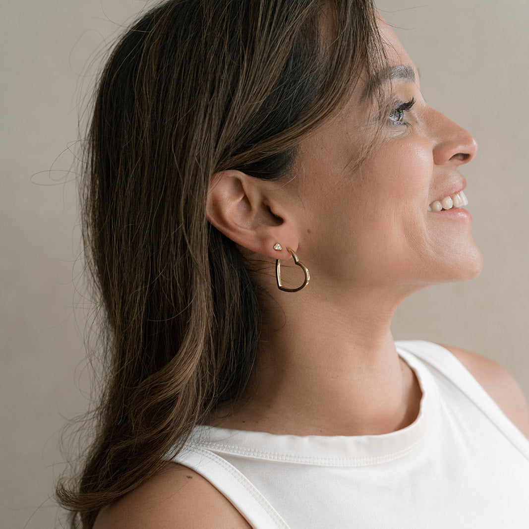Woman wearing gold hoop earrings with a neutral background