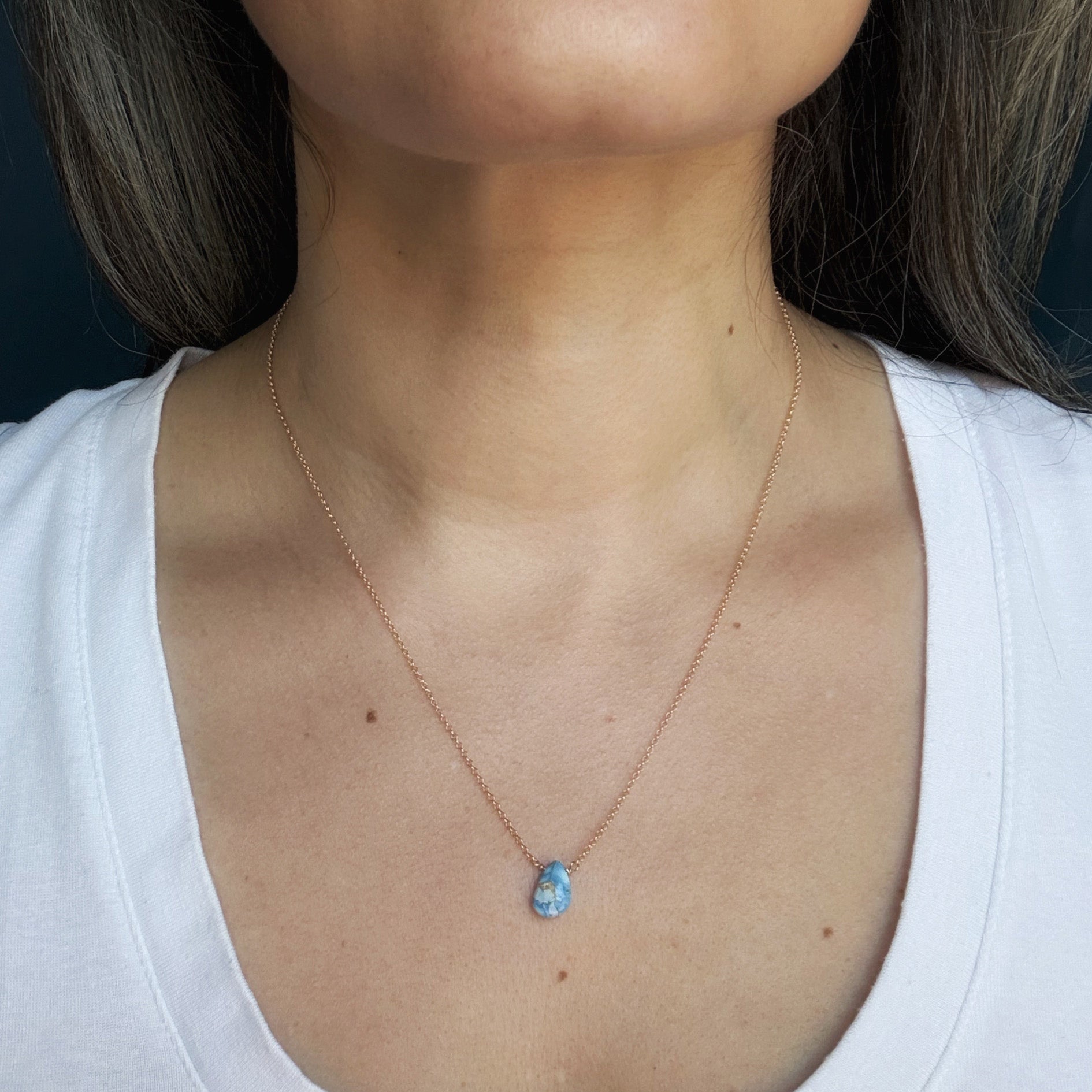 Close up of woman wearing tear drop shaped Golden Hills Turquoise necklace