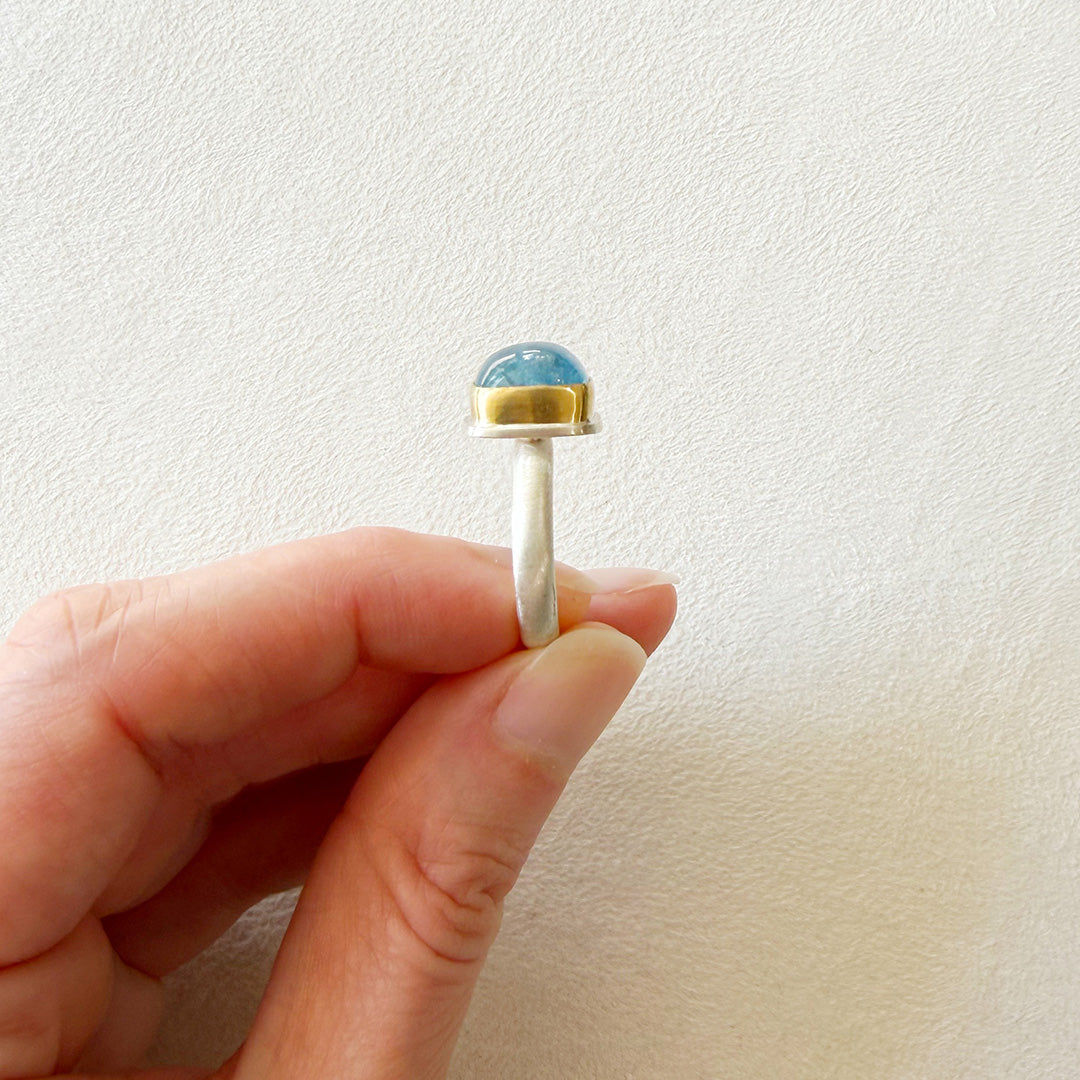 Side view of a smooth cushion cut mixed metal aquamarine ring