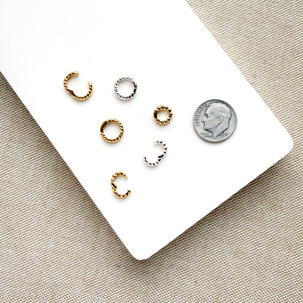 Charm ring enhancers in silver and gold on a white background with a dime for size reference