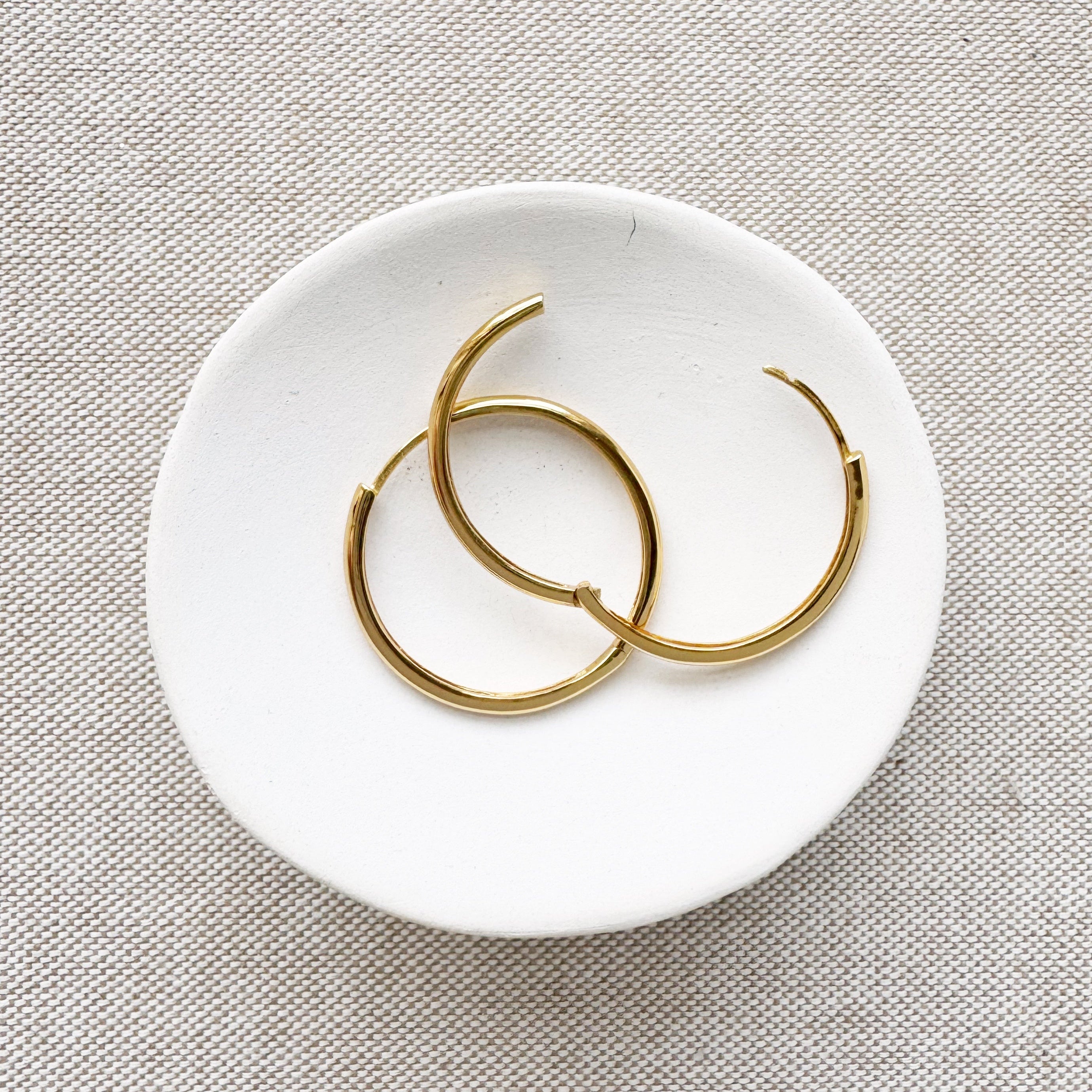 medium gold hoops in a white dish