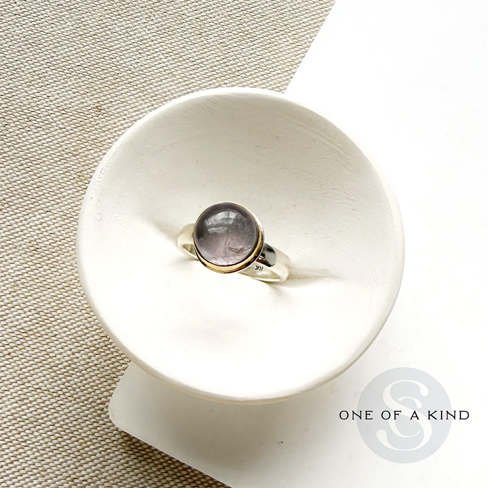 Round berry spinel ring in a mixed metal setting, placed in a white dish