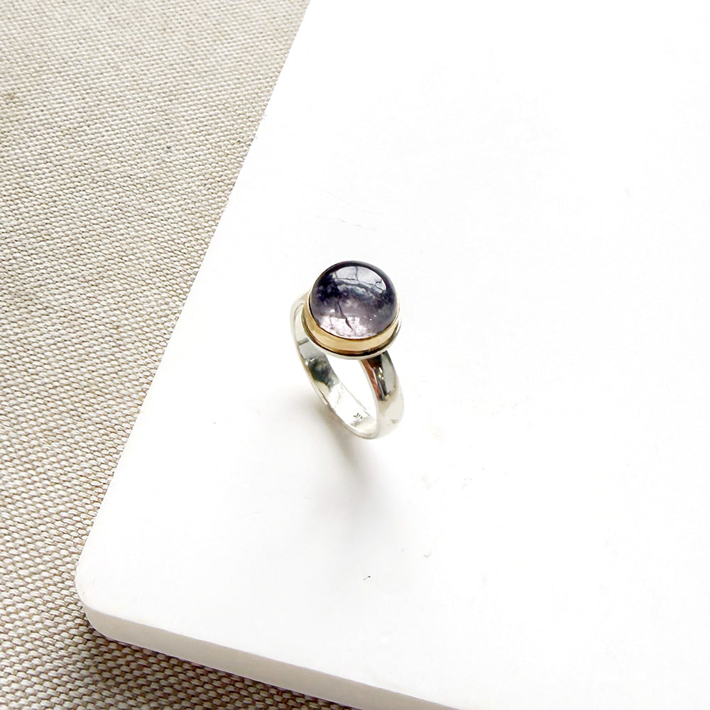 Round berry spinel ring in a mixed metal setting, placed on a white dish
