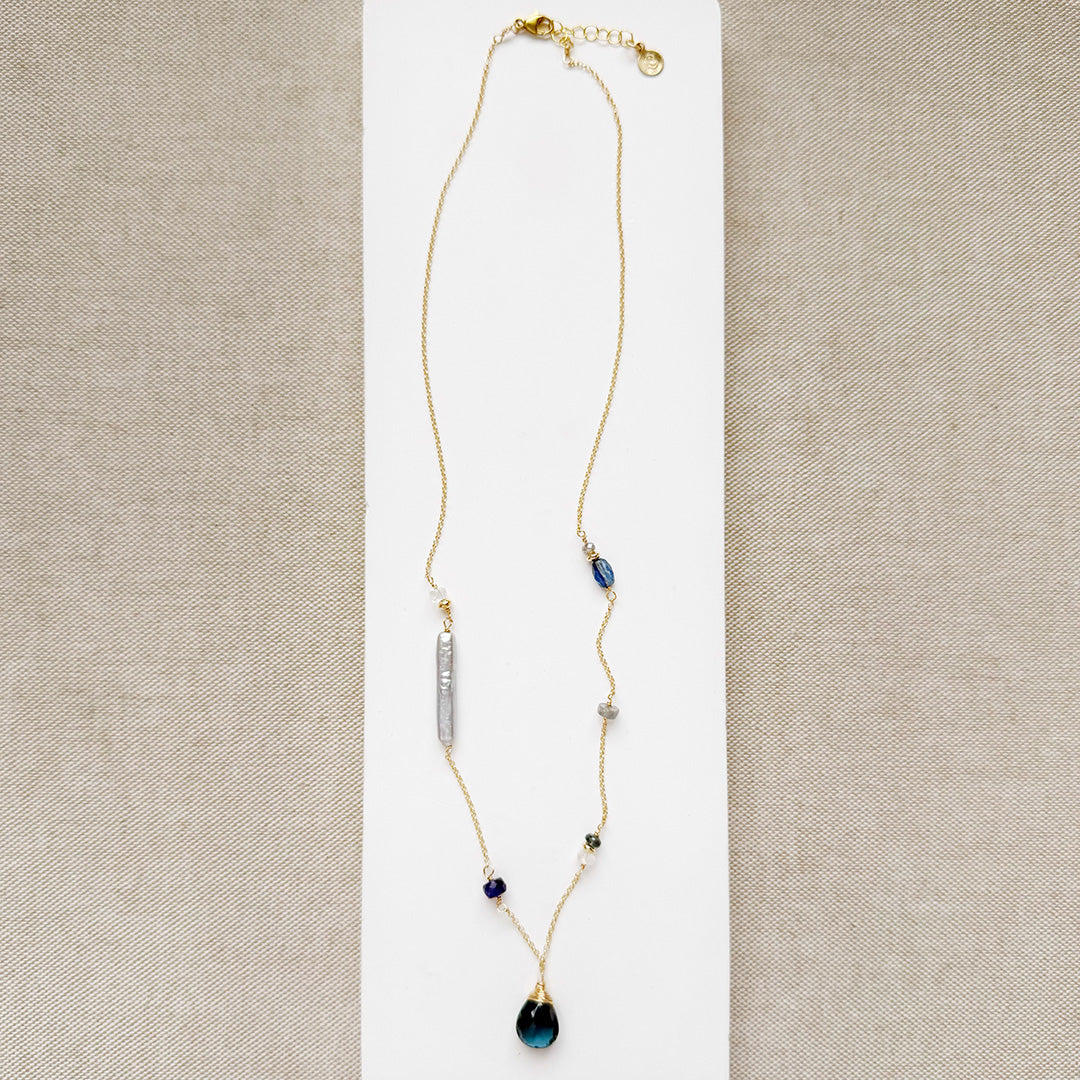 Gold necklace with mixed gems and pearls on a white background