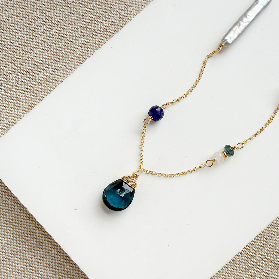 Gold necklace with mixed gems and pearls on a white background