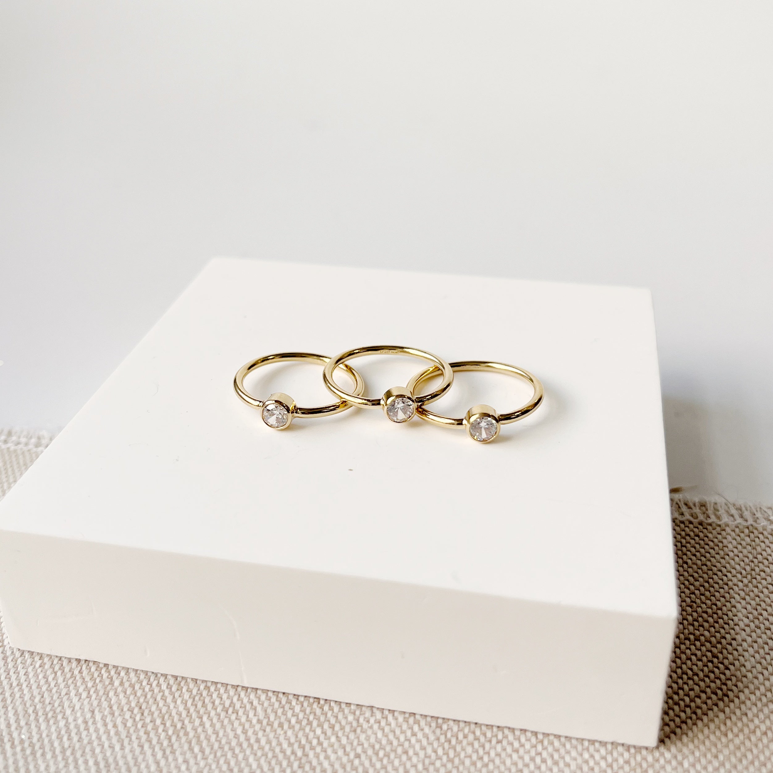 Small gold stacking rings with CZ stones on a white plate