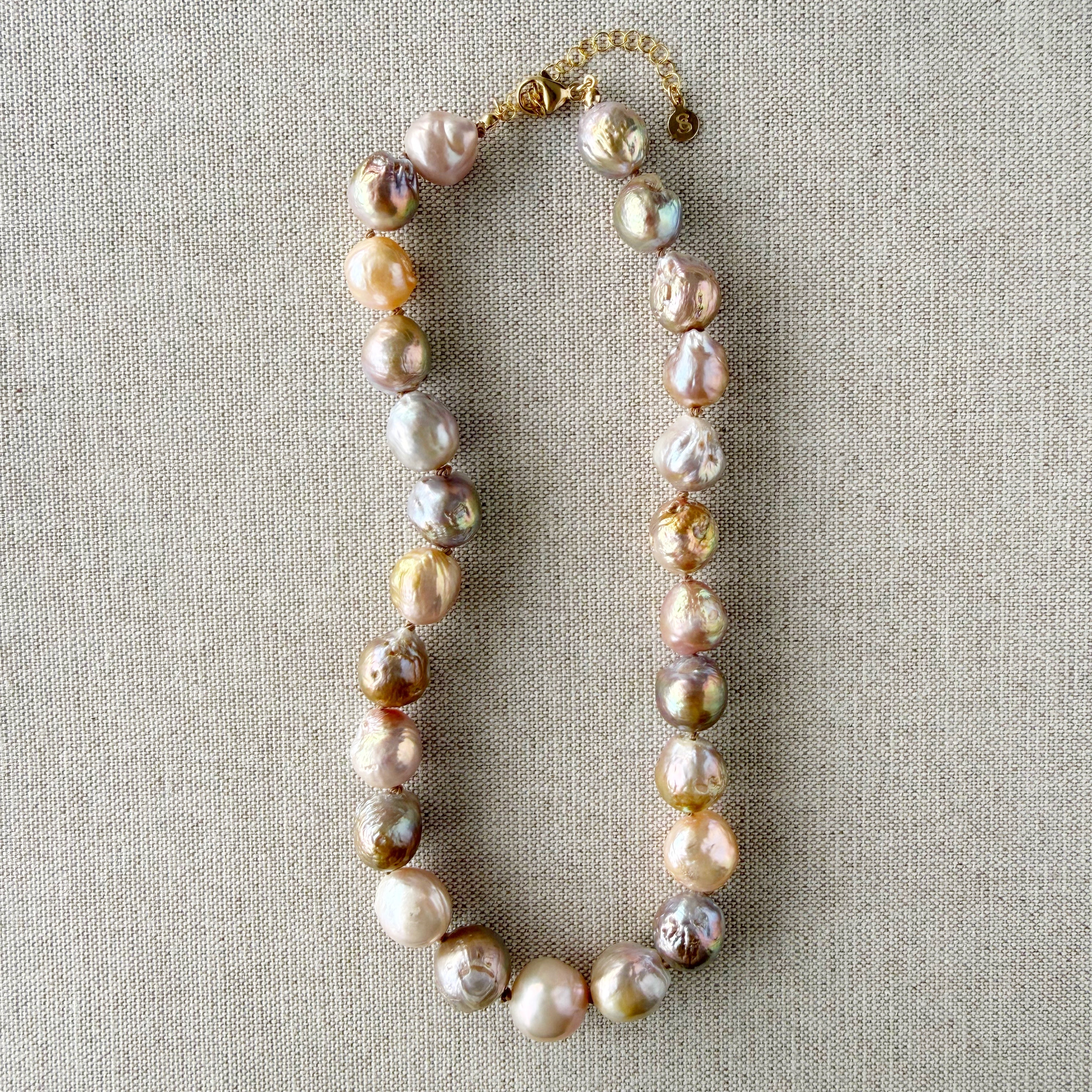 Champagne and rose baroque pearl necklace on a textured beige background