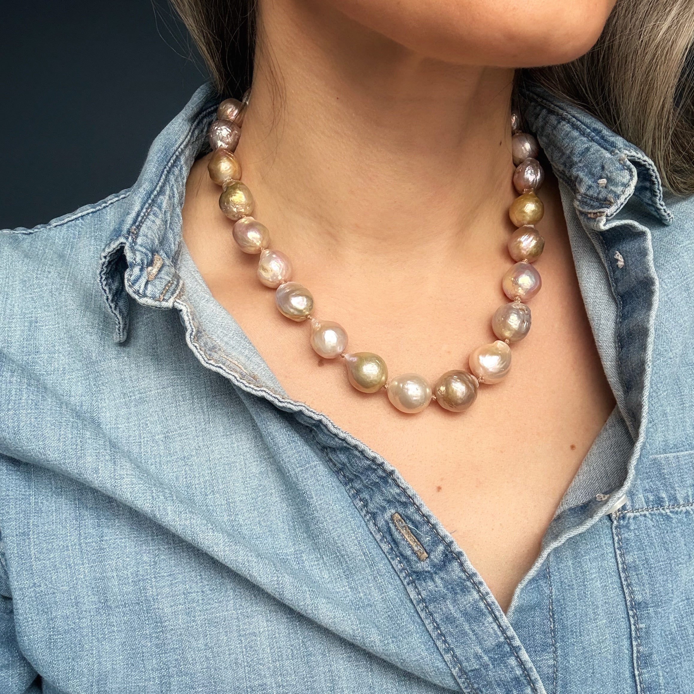 Close up of woman wearing a denim shirt and large champagne baroque pearl necklace