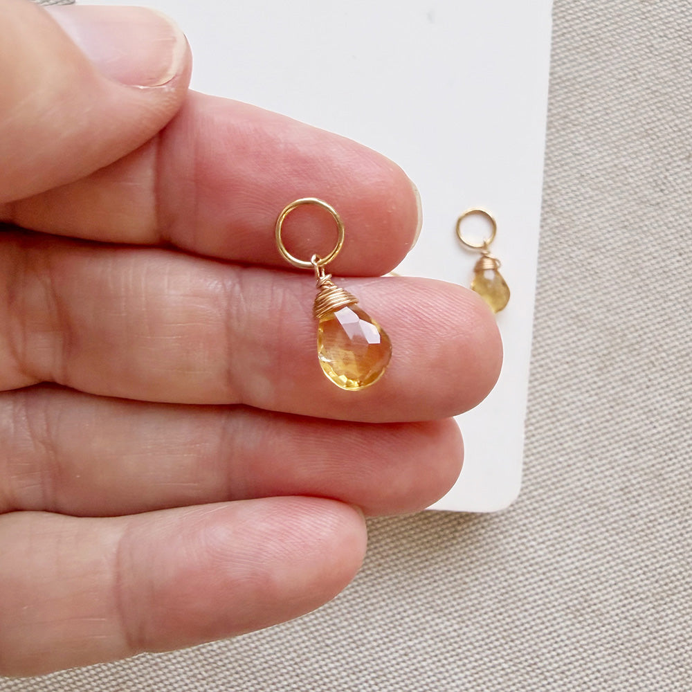 Hand holding a citrine teardrop shaped charm