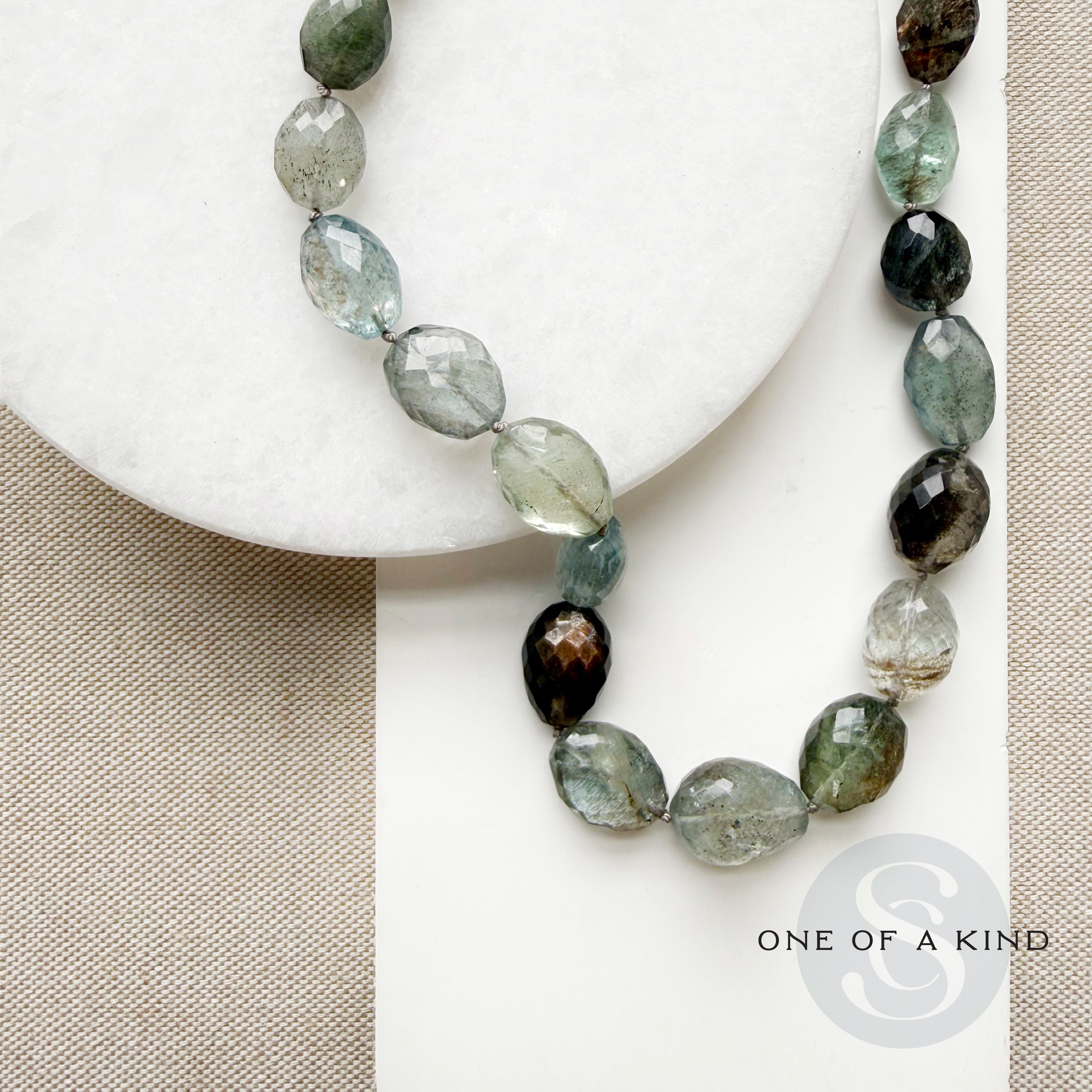 Copper aquamarine necklace on a white plate with one-of-a-kind label