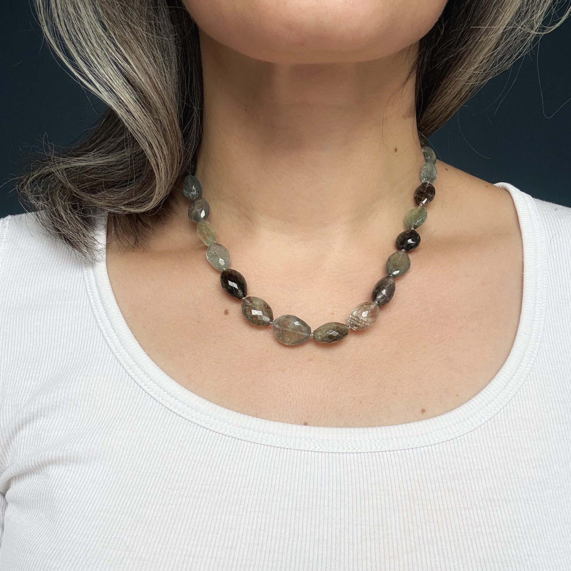 Necklace with copper aquamarine gemstones worn by a person against a dark background