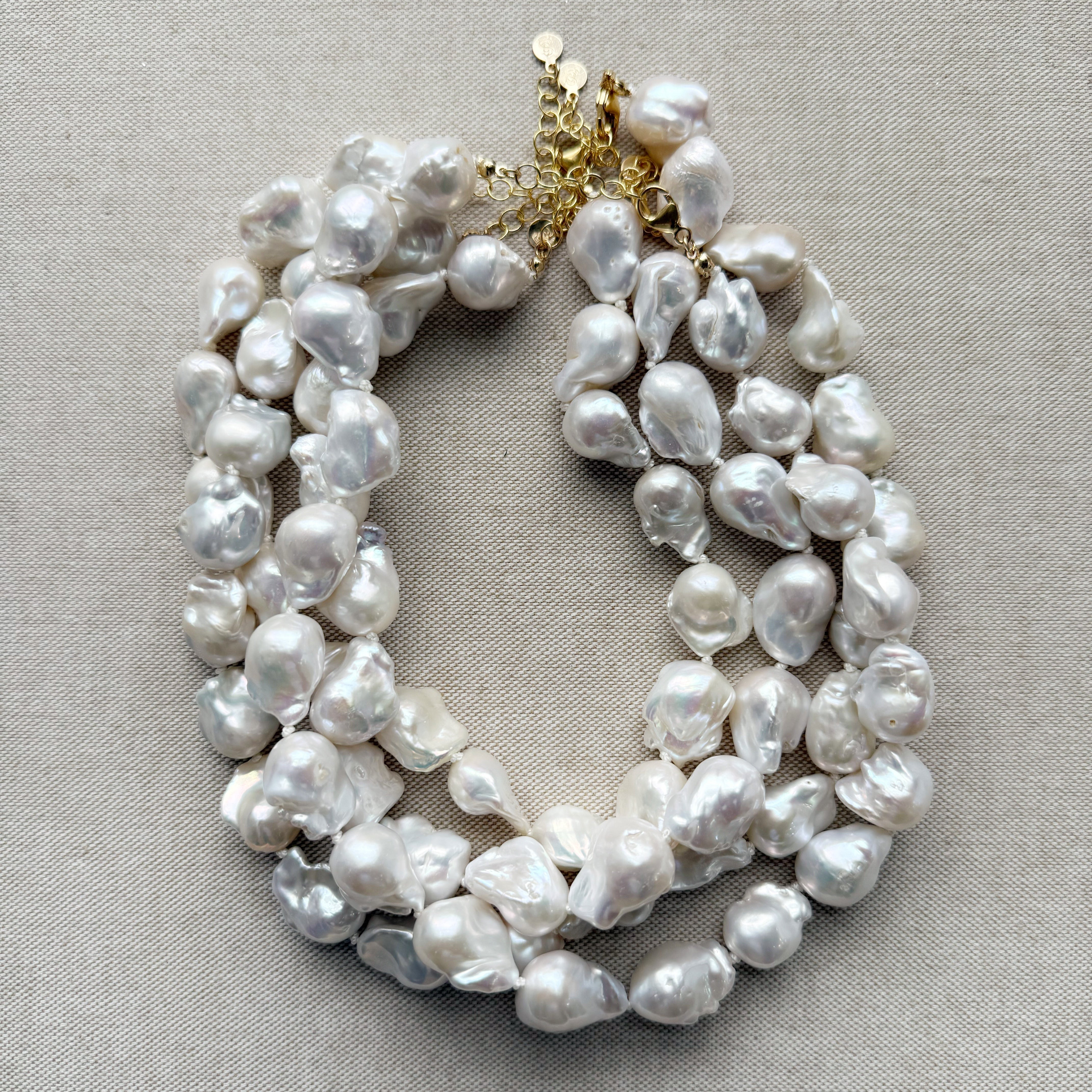 Large baroque pearl necklaces on a white card with a beige background