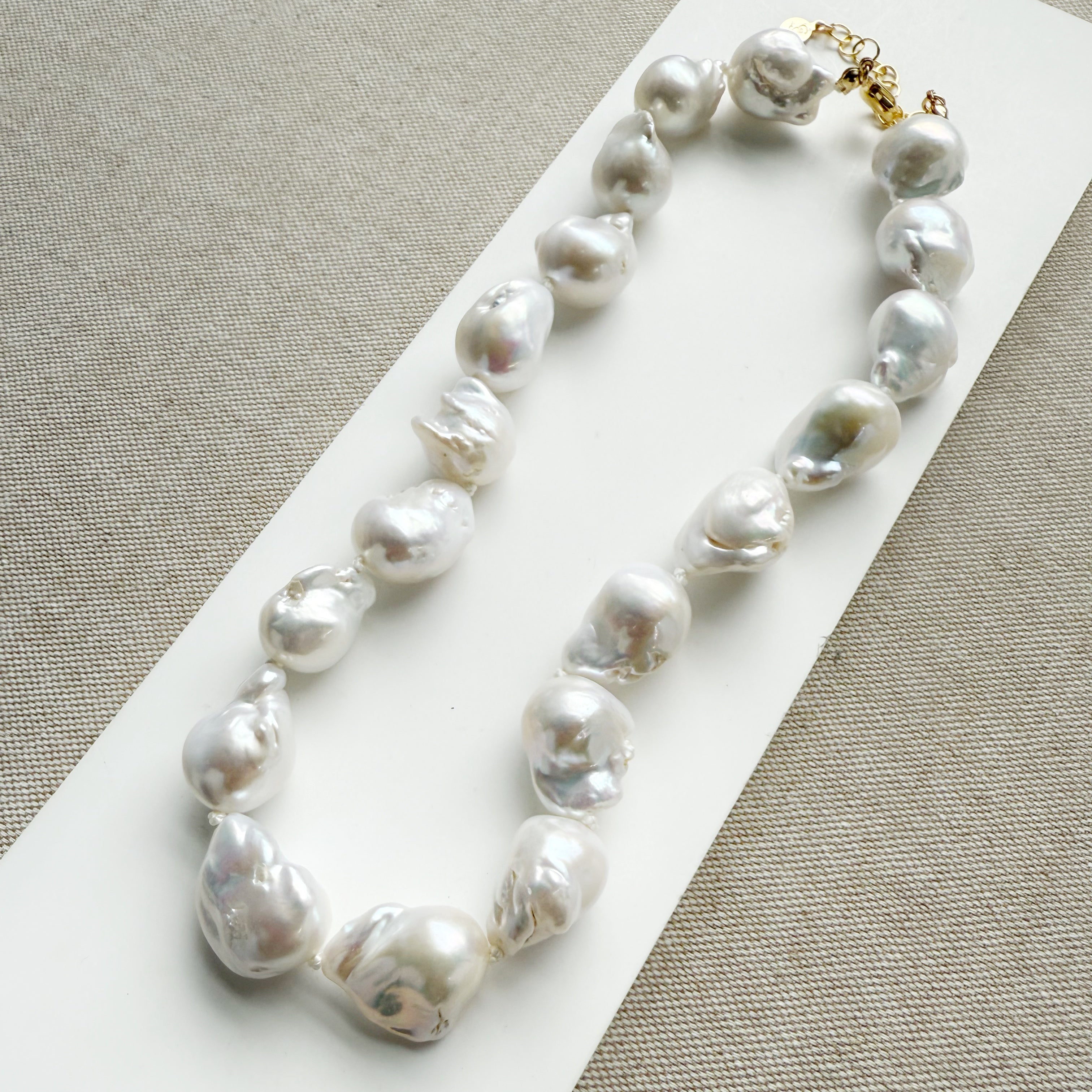 Large baroque pearl necklace on a white card with a beige background