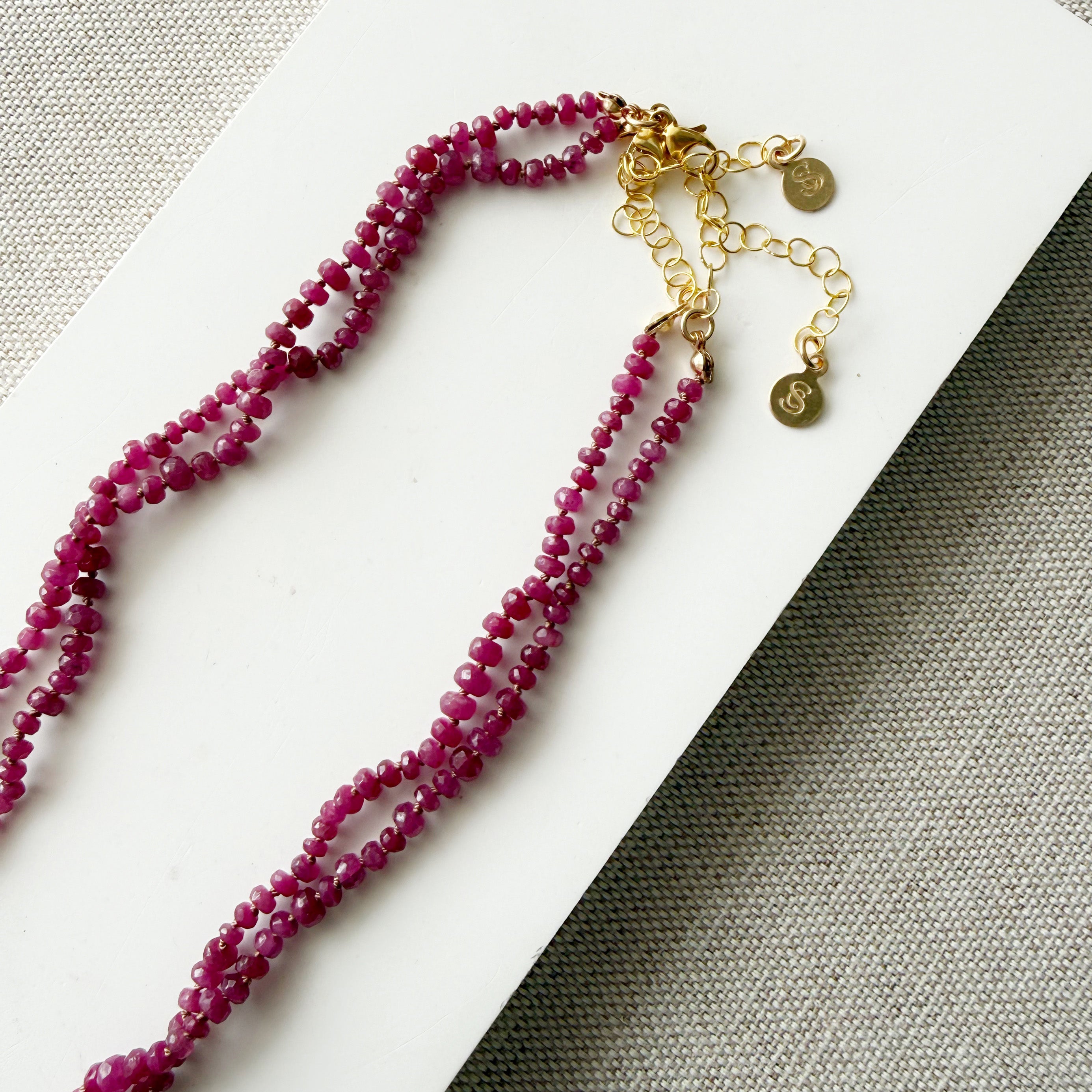 Clasp and extender for small ruby gems knotted necklace on a light gray background