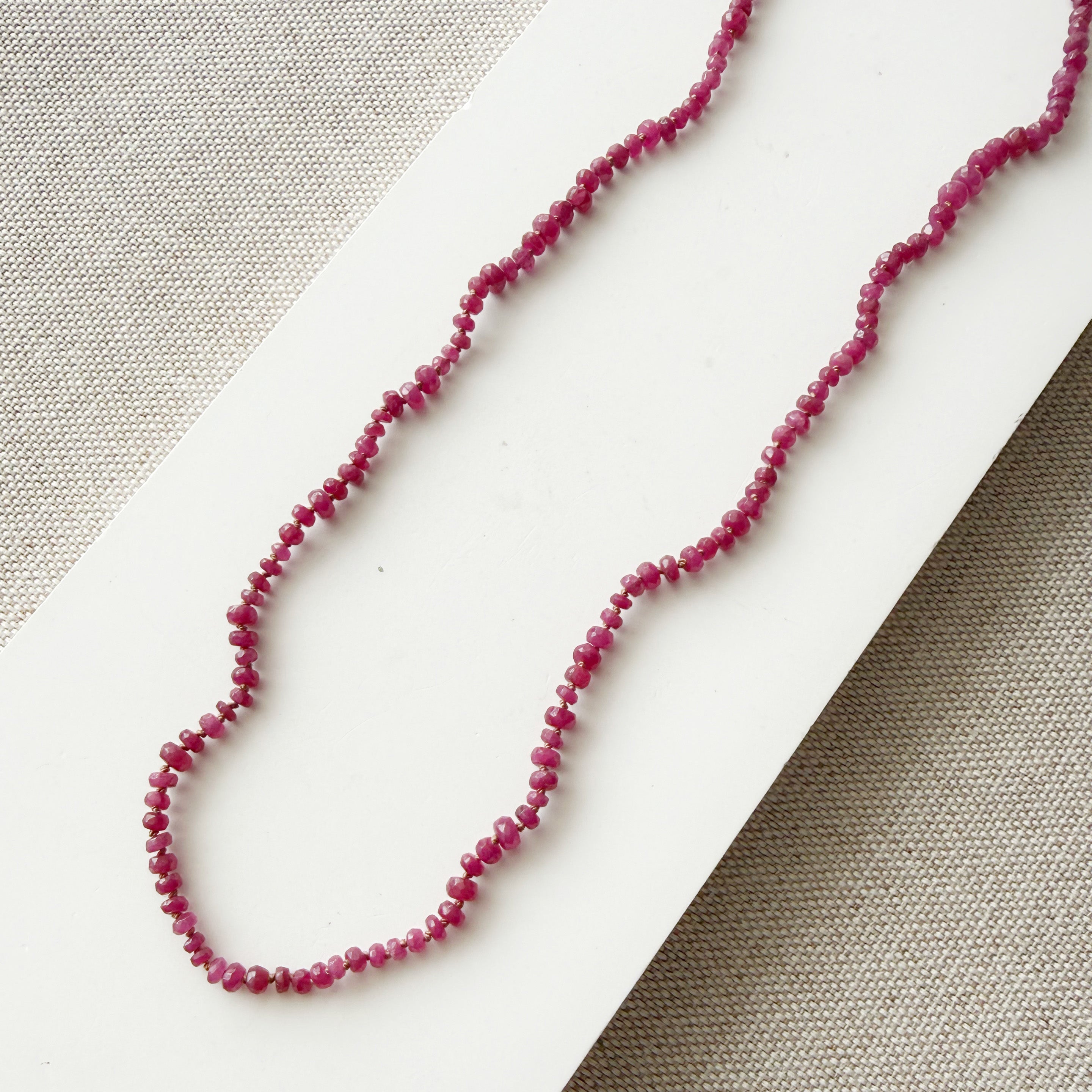 Small ruby gems knotted necklace on a light gray background