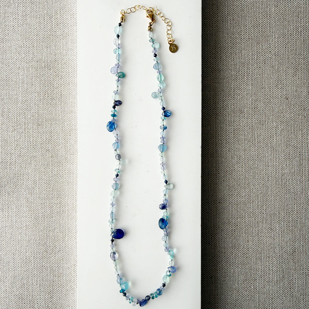 Gemstone necklaces in shades of blue on a white surface