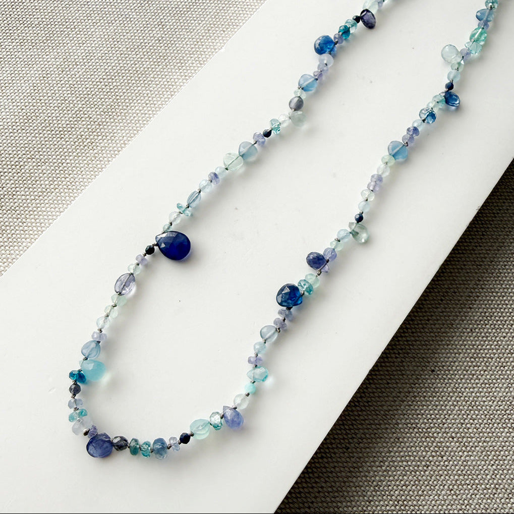 Gemstone necklaces in shades of blue on a white surface