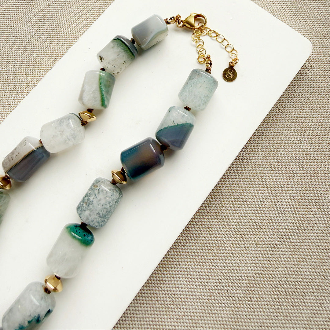 Necklace with green and gray beads on a white card