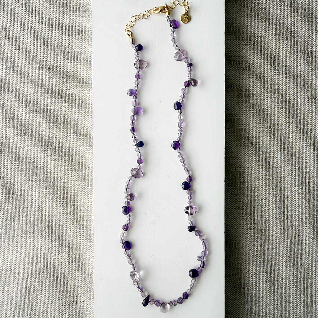Gemstone necklace in shades of purple on a white surface