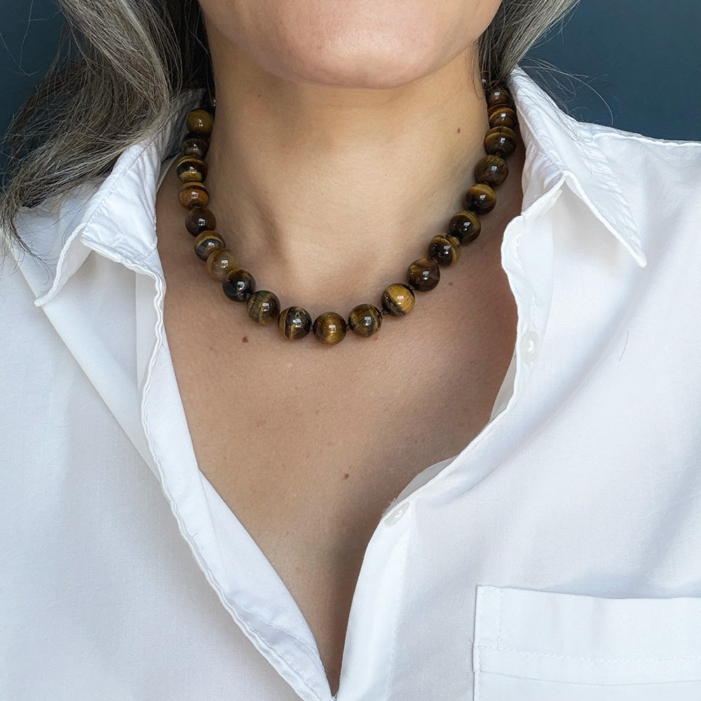 Woman wearing large Tigers Eye knotted gemstone necklace with a white shirt