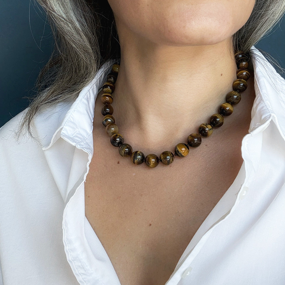 Woman wearing large Tigers Eye knotted gemstone necklace with a white shirt