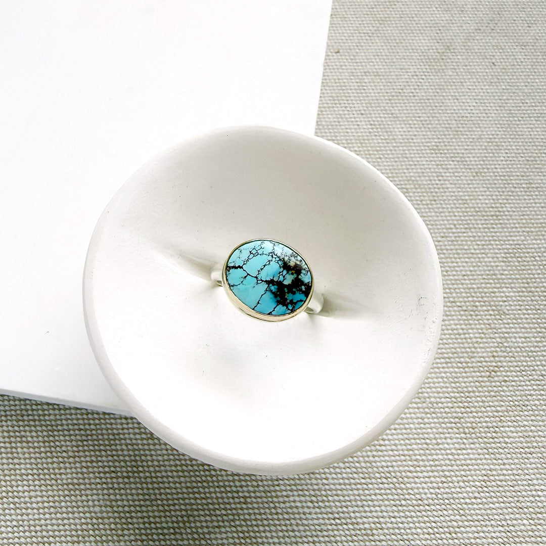 One of a kind Golden Hills turquoise mixed metal ring in a white dish