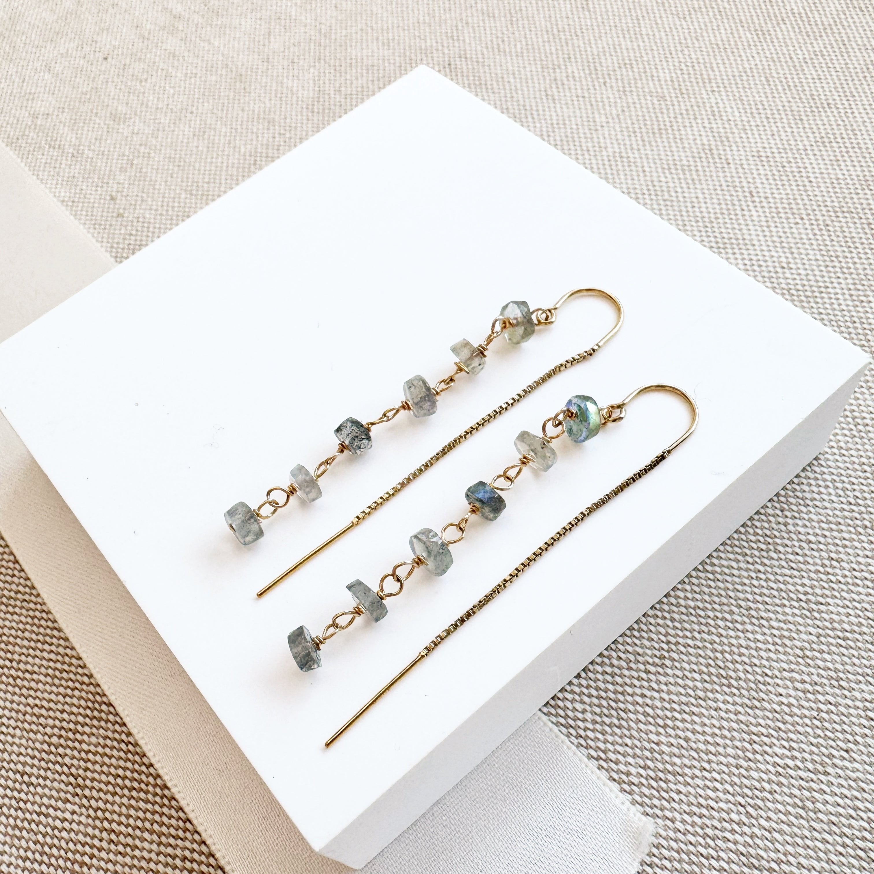 Gold threader earrings with labradorite stones on a white background