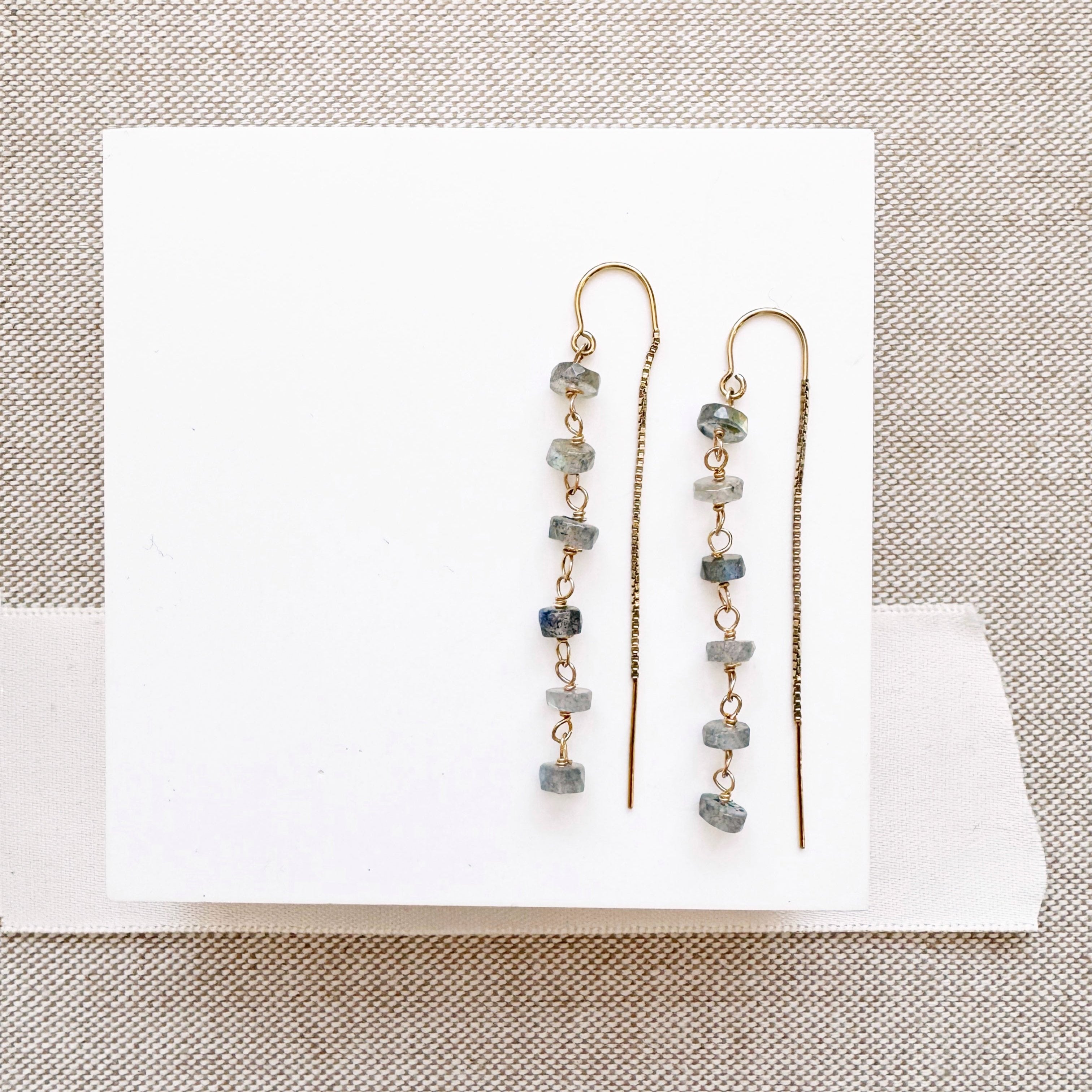 Gold threader earrings with labradorite stones on a white background