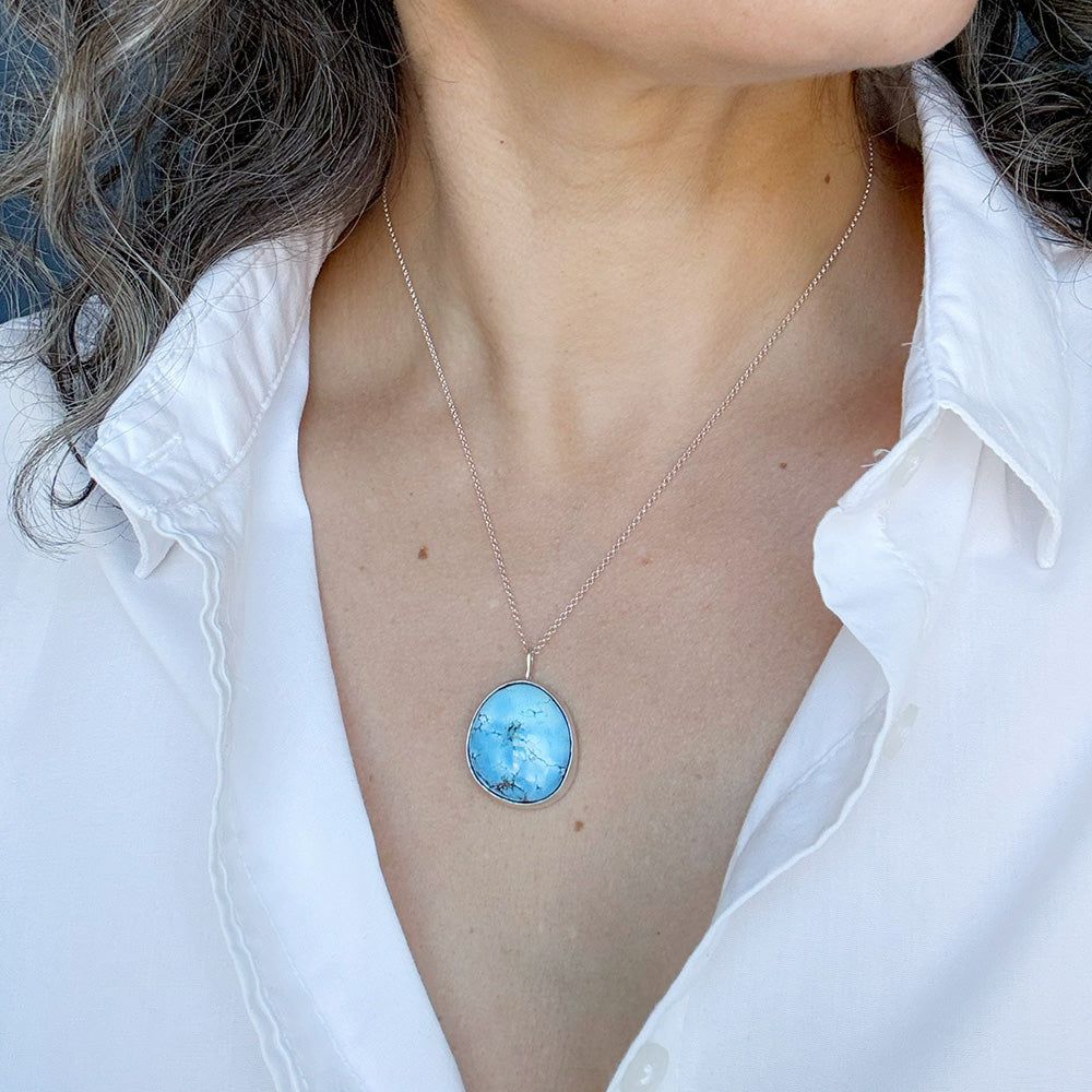 Woman wearing Golden Hills Pendant set in sterling silver with a white shirt