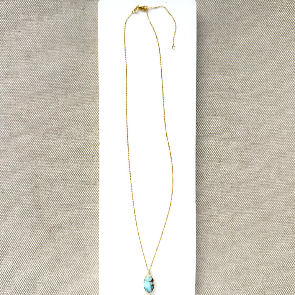 Small oval Golden Hills Pendant set in solid gold on a white plate