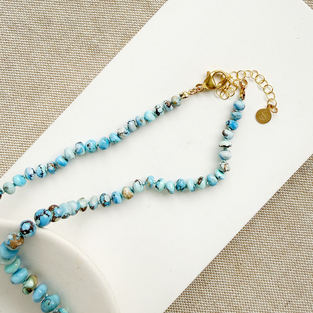 Clasp detail of Golden Hills Turquoise knotted necklace on a white plate