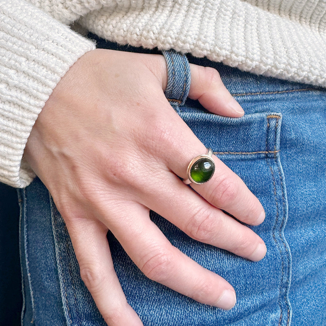 Hand wearing a green tourmaline mixed metal ring