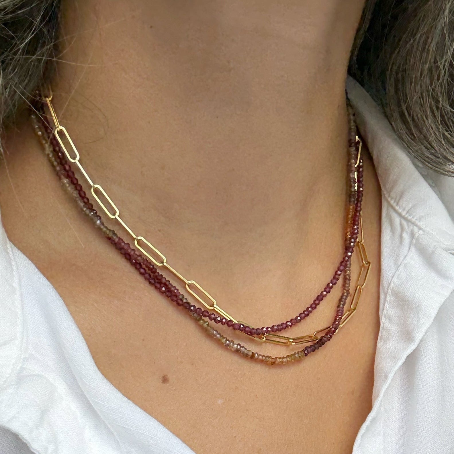 Necklace with red beads worn by a person in a white shirt