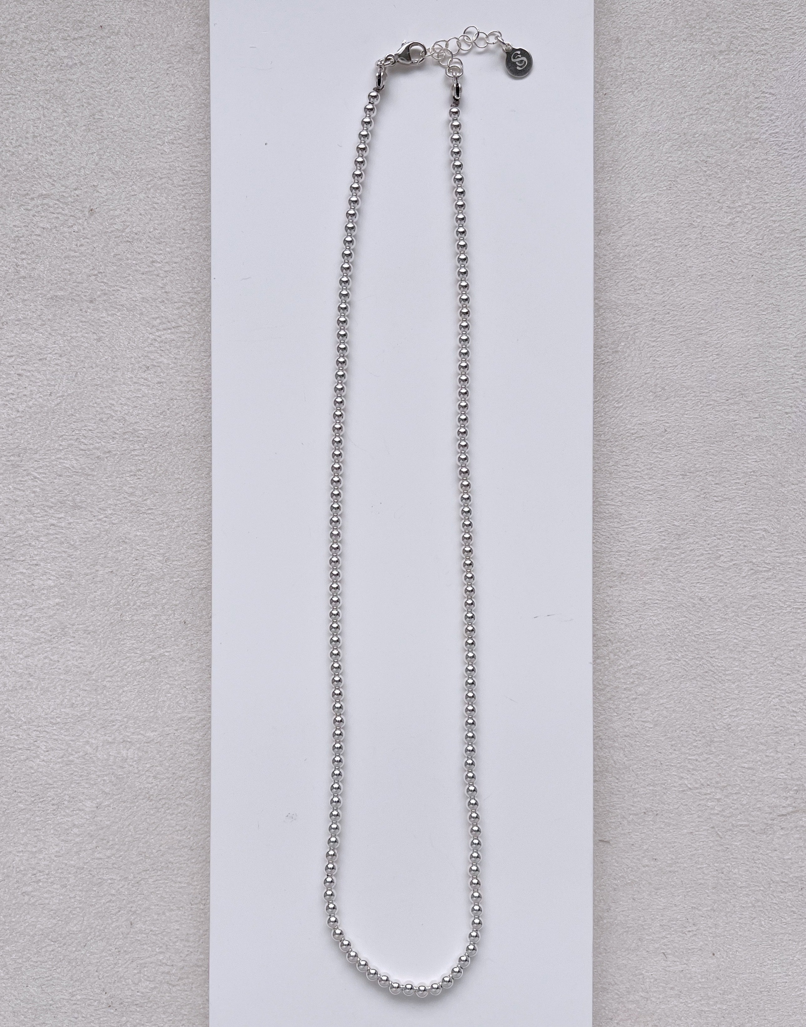Silver beaded necklace on a white background