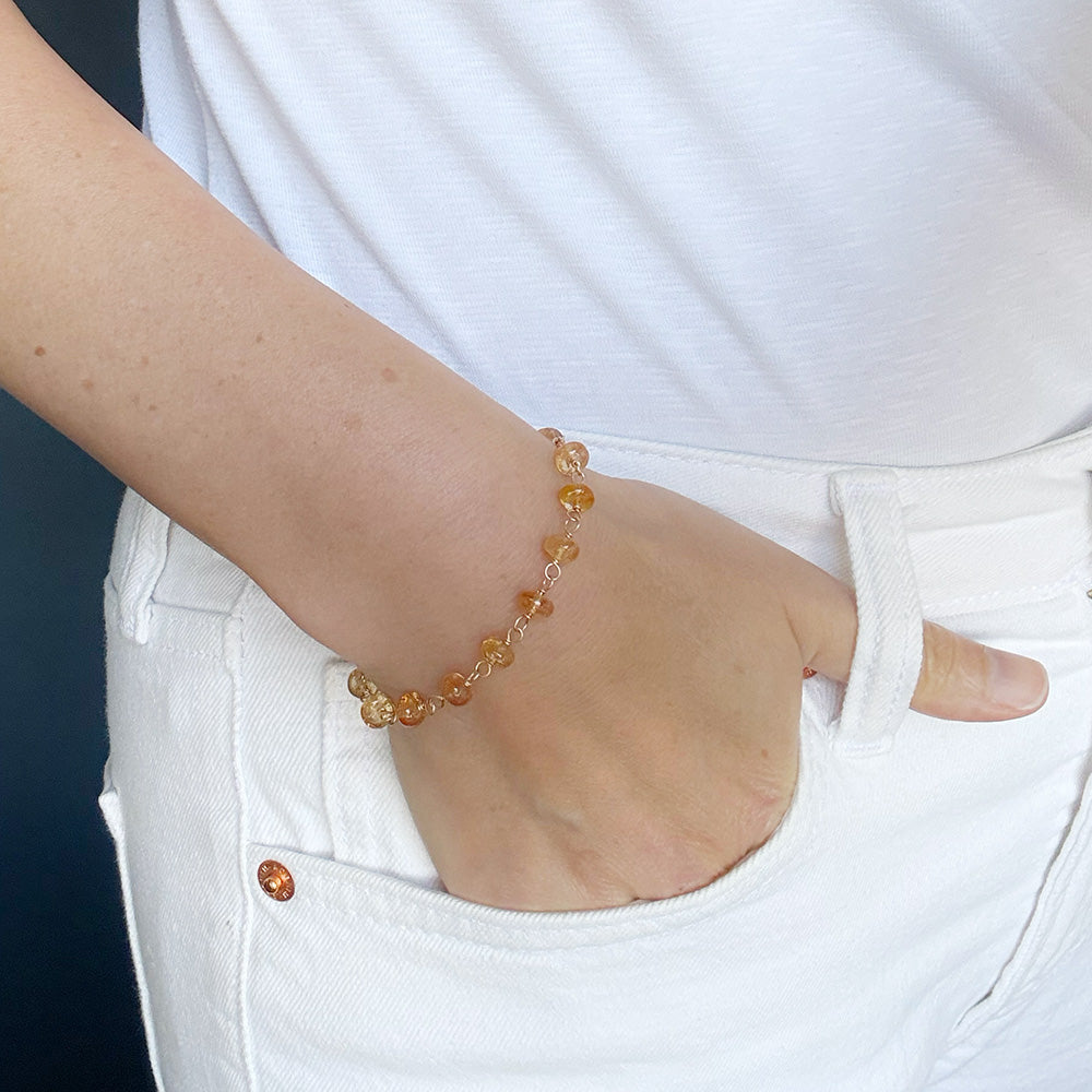 Woman wearing Imperial topaz bracelet on a blue background