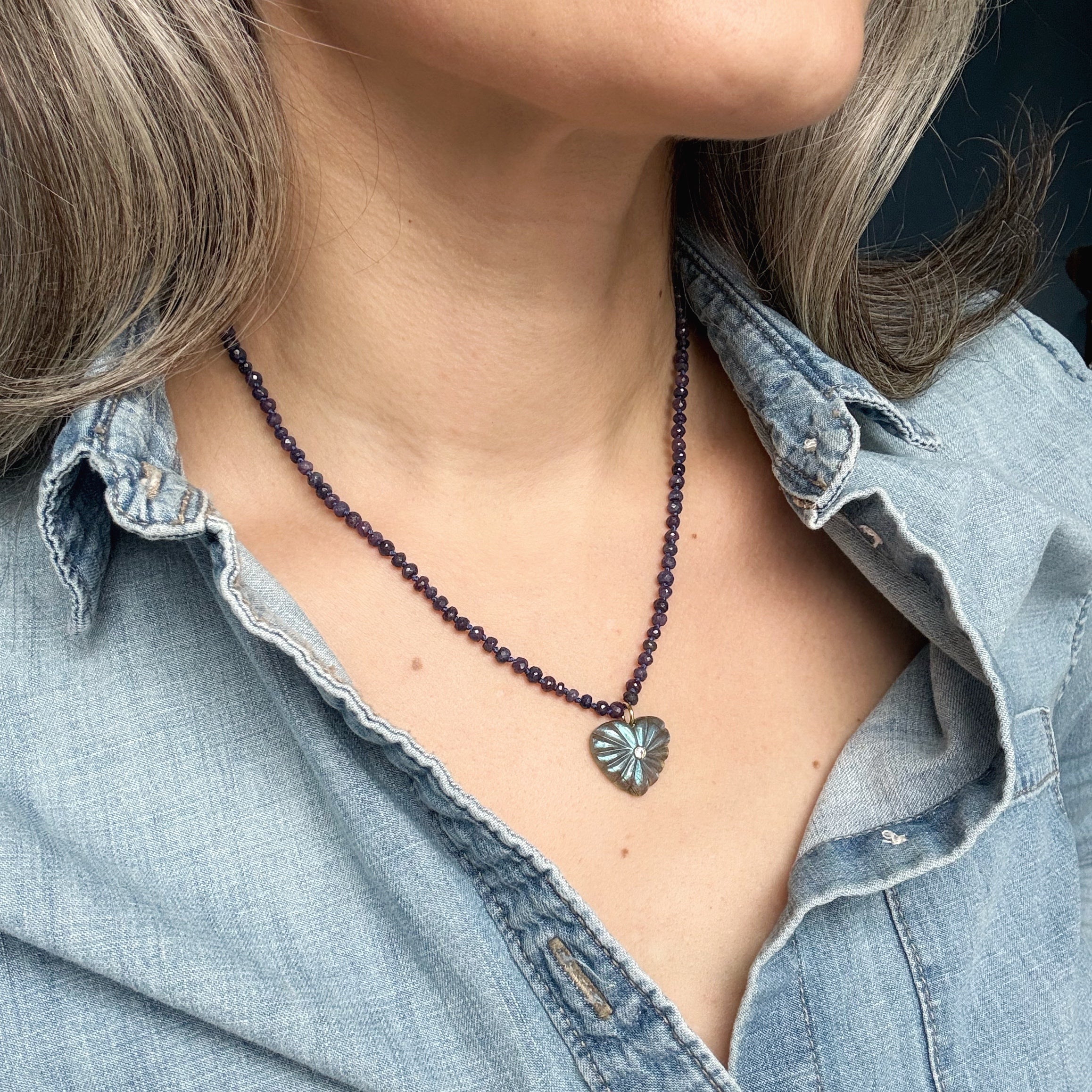 Close up of woman wearing gemstone necklace with carved pendant