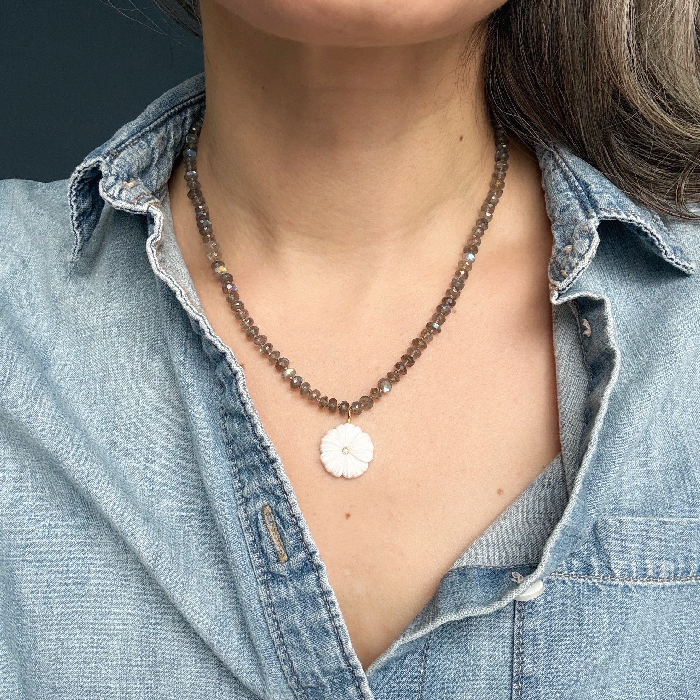 Close up of woman wearing gemstone necklace with carved pendant