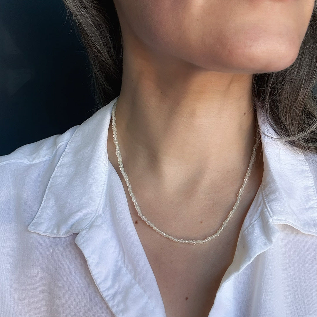Person wearing a lemon quartz beaded gem necklaces with a white shirt against a dark background