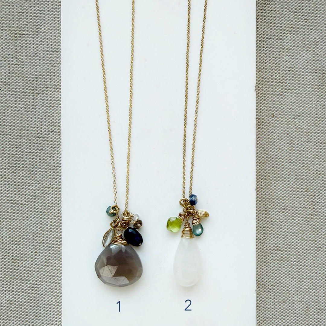 Two long gemstone cluster necklaces in gold on a white background