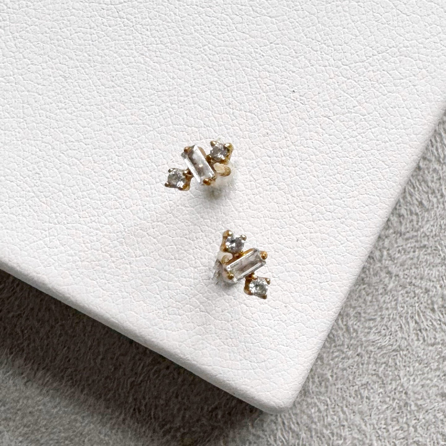 Pair of CZ stud earrings on a white dish with a light gray background