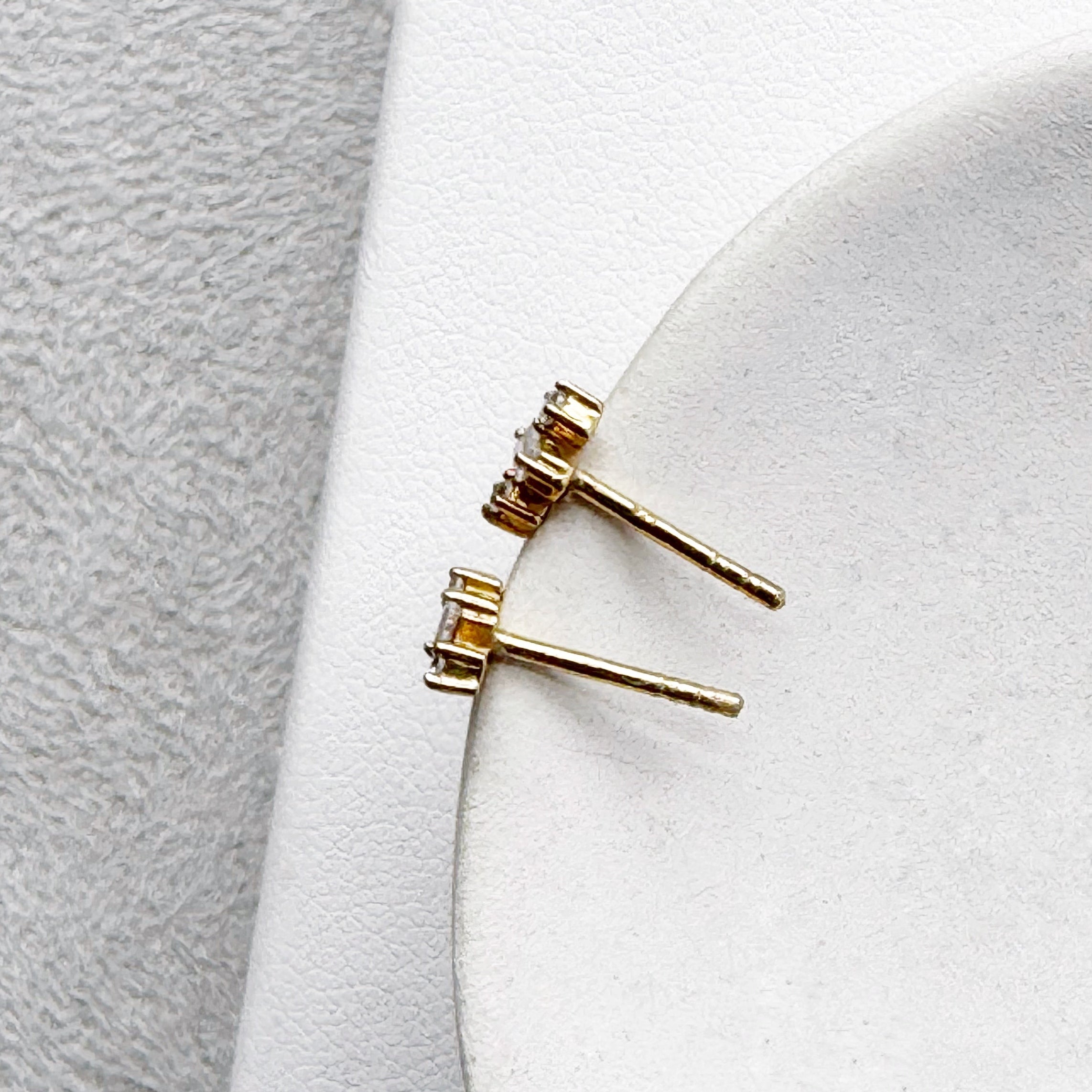 Pair of CZ stud earrings on a white dish with a light gray background