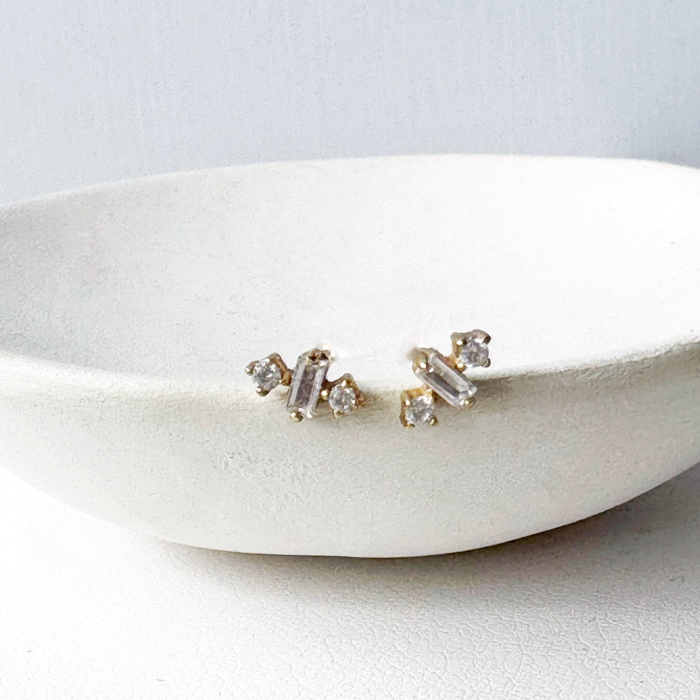 Pair of CZ stud earrings on a white dish with a light gray background