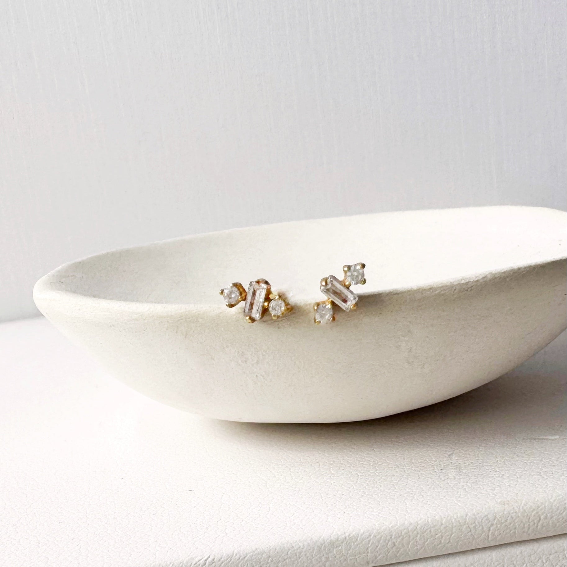 Pair of CZ stud earrings on a white dish with a light gray background