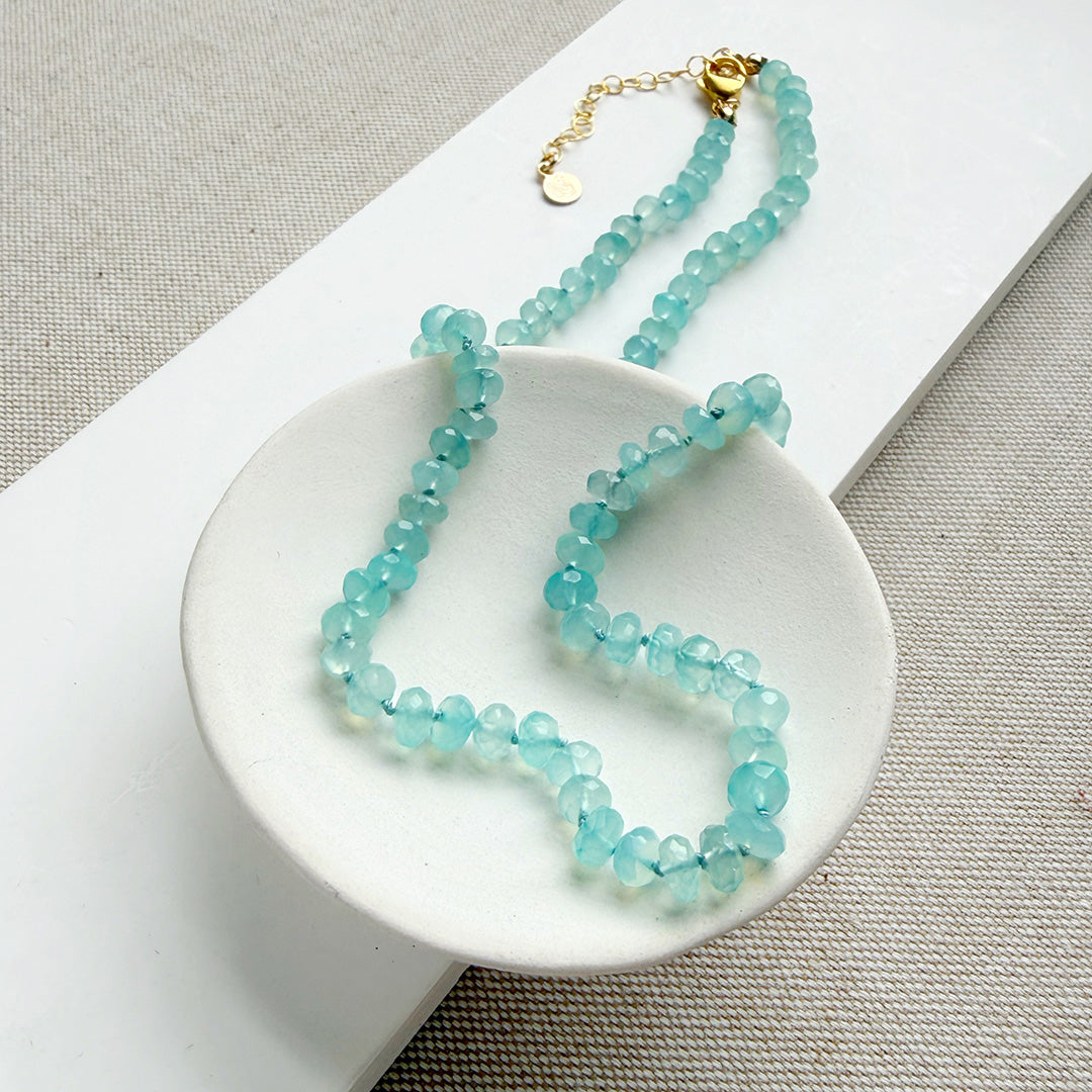 Aqua chalcedony beaded necklace on a white dish with a neutral background