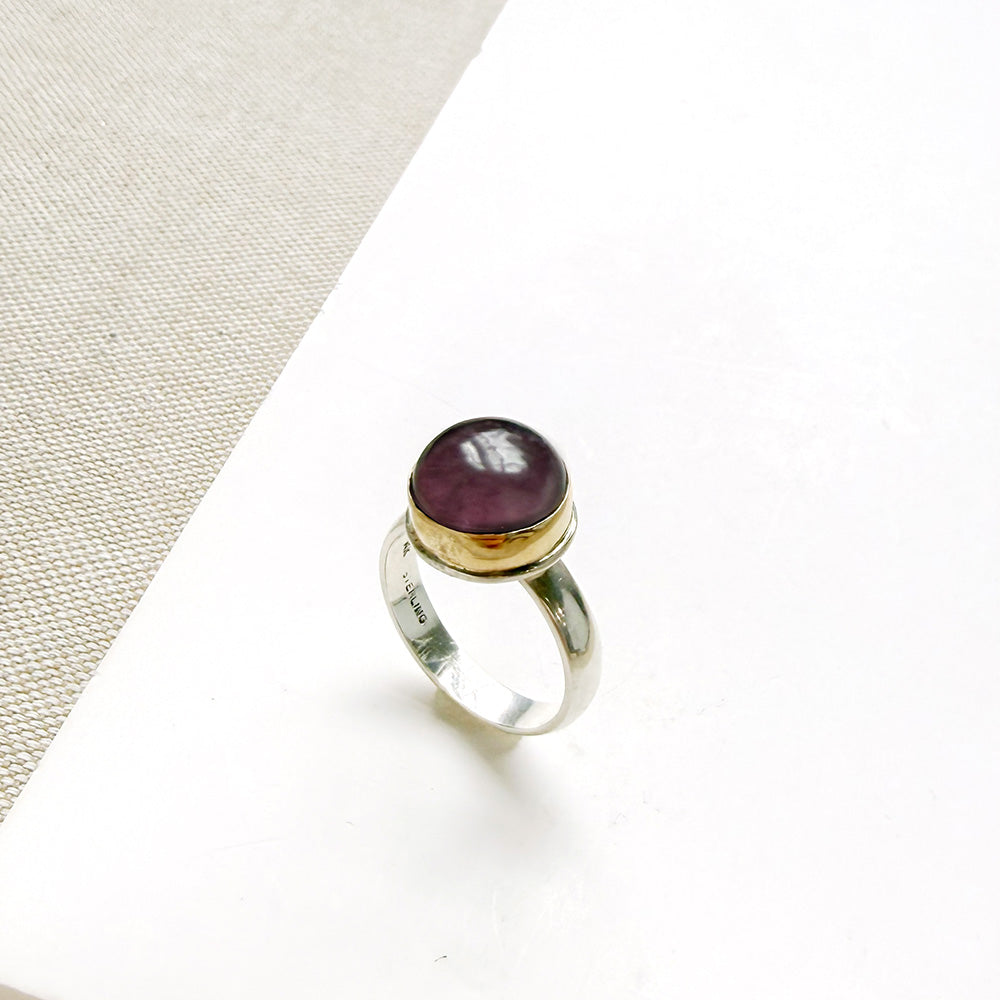 Round smooth cut mauve spinel ring on a white dish