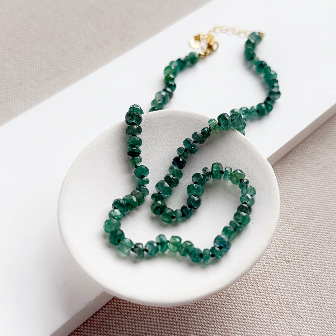 Green kyanite gemstone necklace on a white dish with a neutral background